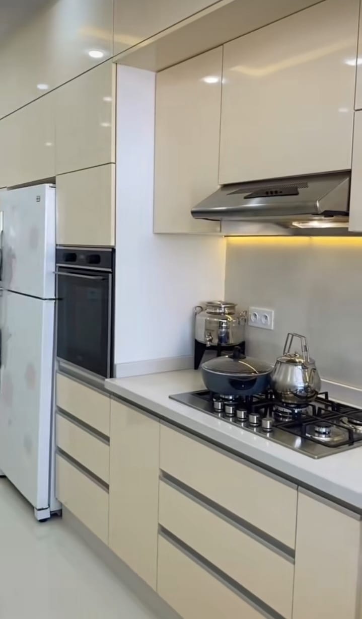 Cuisine moderne avec mobilier intégré, four encastré et éclairage LED sous les meubles hauts — réalisée par Jouissance